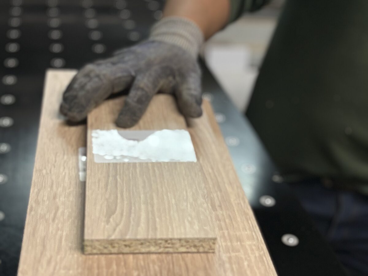 Operario aplicando acabado UV sobre puerta de madera